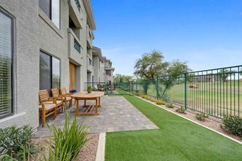 a patio with a table and chairs in front of a building